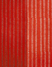 Close up of vibrant red textile featuring vertical rows of white leaf patterns in Los Angeles casting by Lilac Perez.