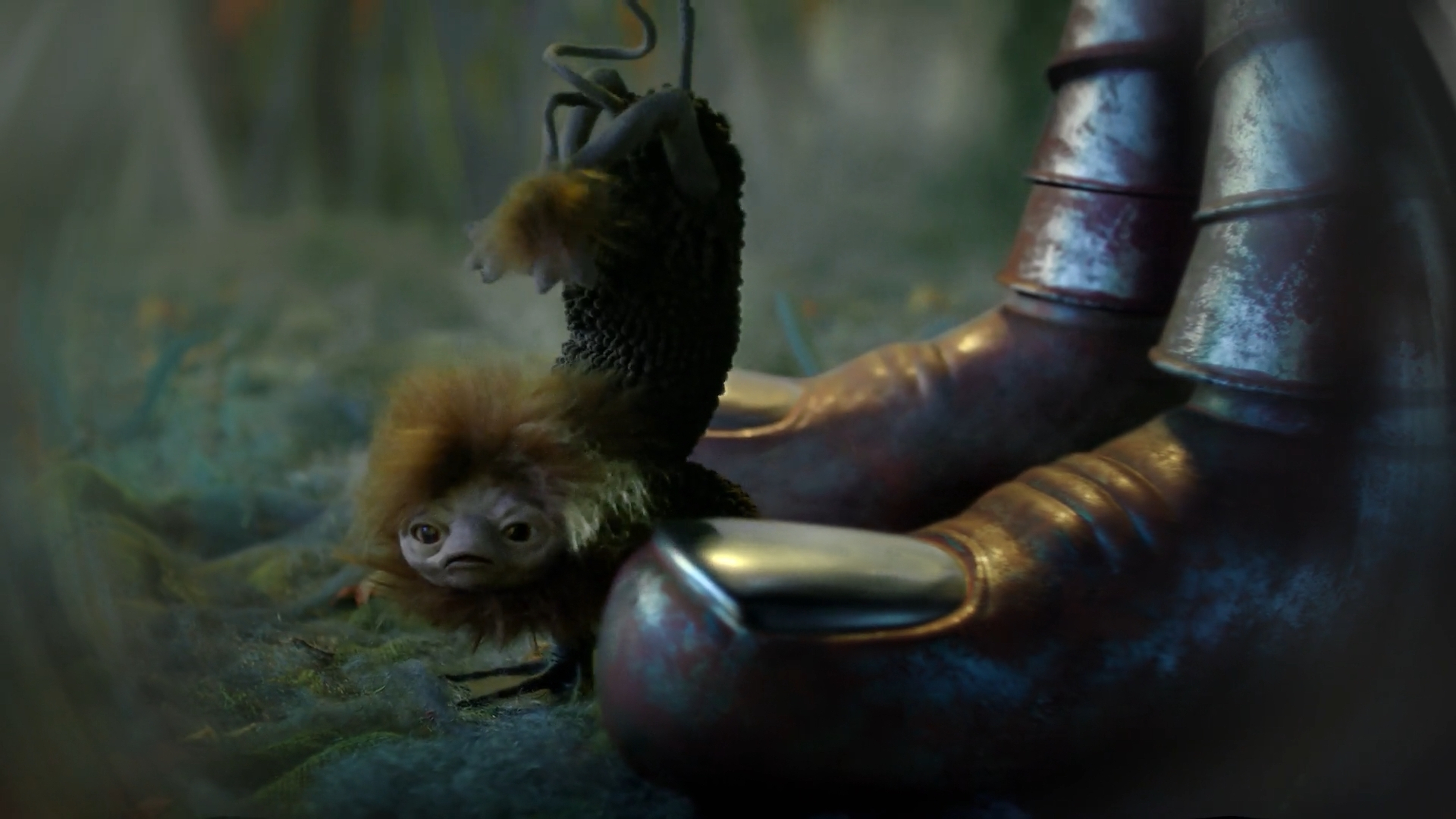 Close-up of Niffler-like creature with brown fur and large eyes, hanging by a wire near metallic boots in a muted color environment.