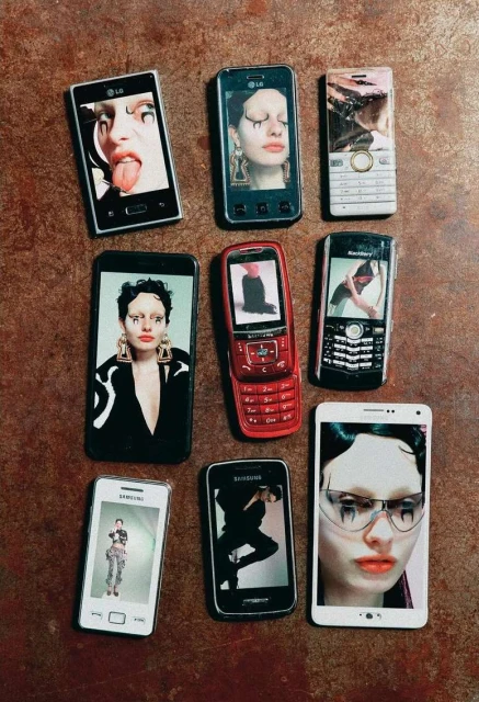 Nine vintage cell phones displayed on a textured brown surface show different photos of a model with avant-garde makeup.