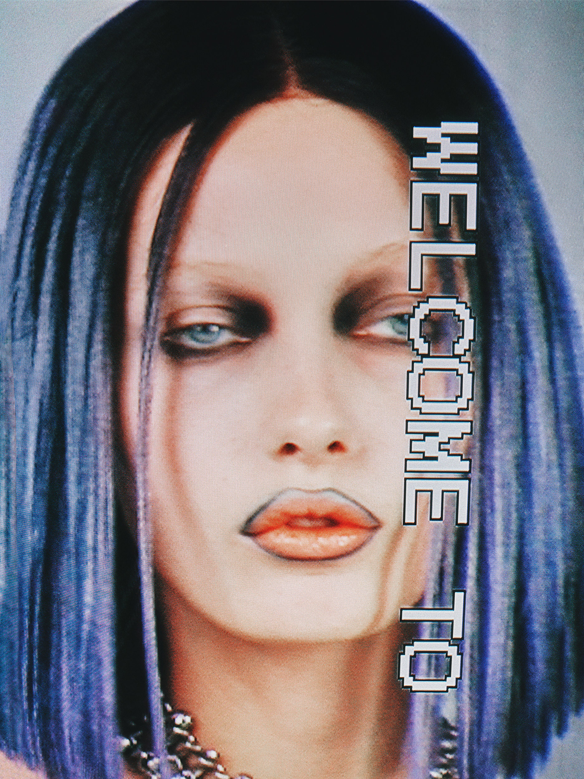 Close-up of a woman with dark hair and blue highlights, heavy makeup, and a silver chain necklace against a blurred background. Welcome to text.