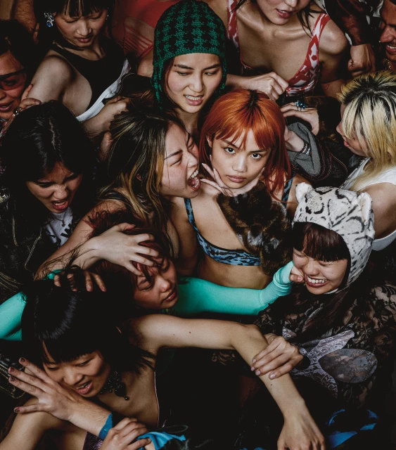 A group of young, stylish Asian women gather closely, showcasing diverse fashion and joyful expressions in a vibrant, eye-level studio portrait.