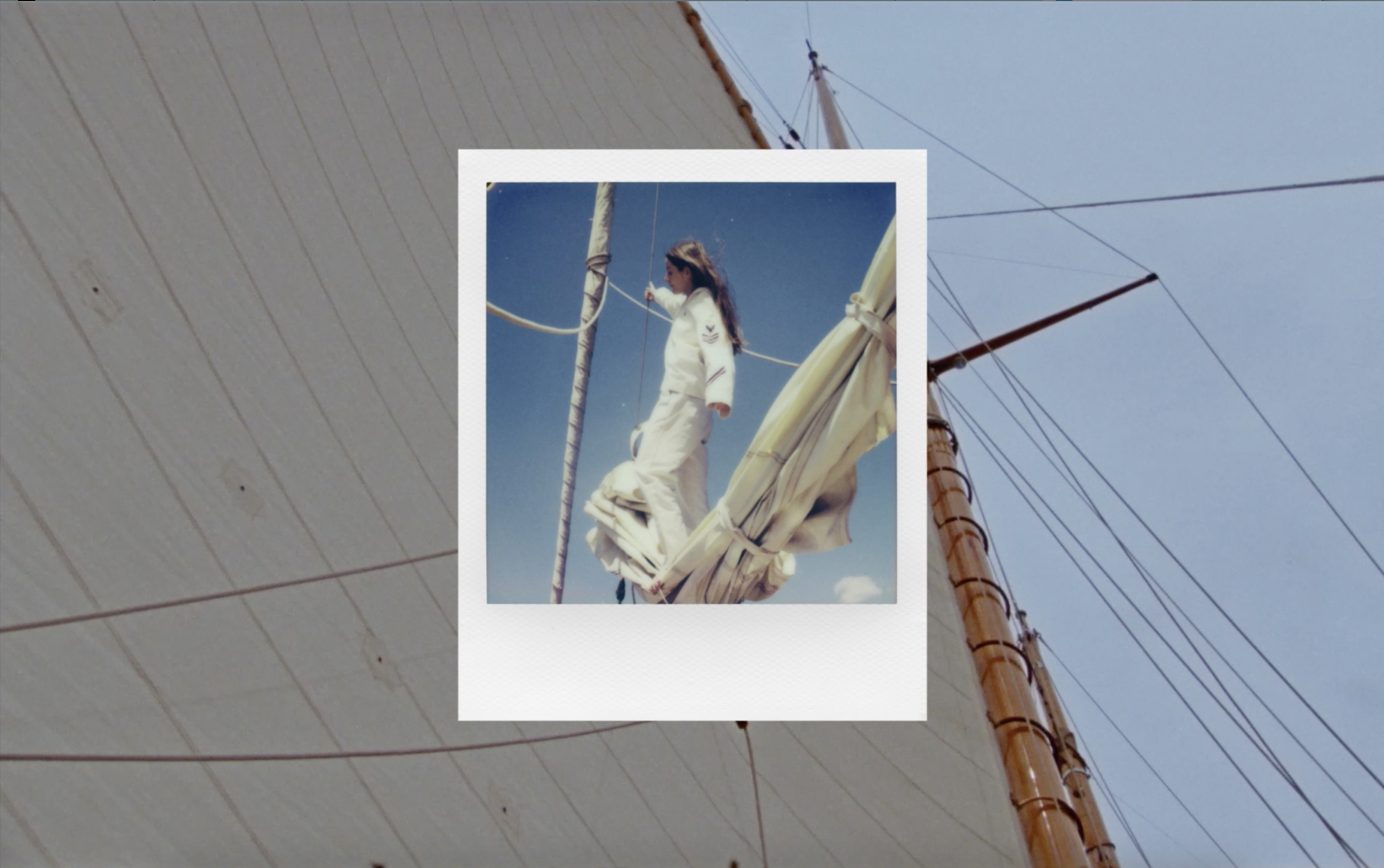 Retro Polaroid image features a woman in white standing on a vintage sailboat, captured against a backdrop of the sail and blue sky.
