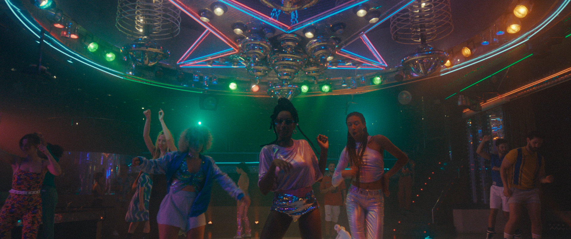 Dynamic scene captures people dancing in a vibrant nightclub, featuring disco balls, neon lighting, and stylish attire, creating a lively atmosphere.