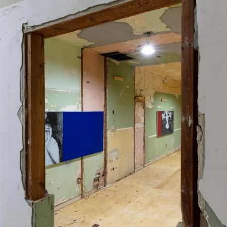 Hallway featuring art, distressed walls, and doorway; creating a visual experience of decay and artistic expression within an interior space.