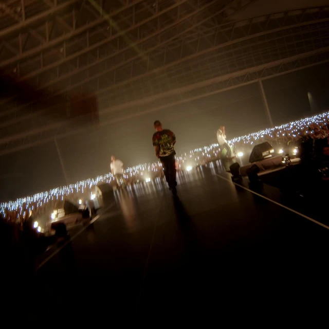 People perform on a stage with bright lights, creating a dynamic and energetic atmosphere in a large indoor venue.