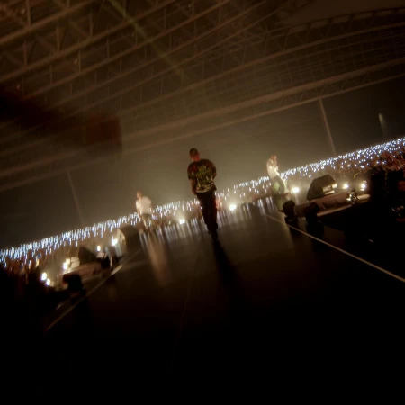 People perform on a stage with bright lights, creating a dynamic and energetic atmosphere in a large indoor venue.