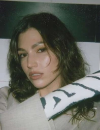 Close-up portrait of a woman with dark wavy hair and neutral makeup wearing a beige blazer, photographed by Stillz.