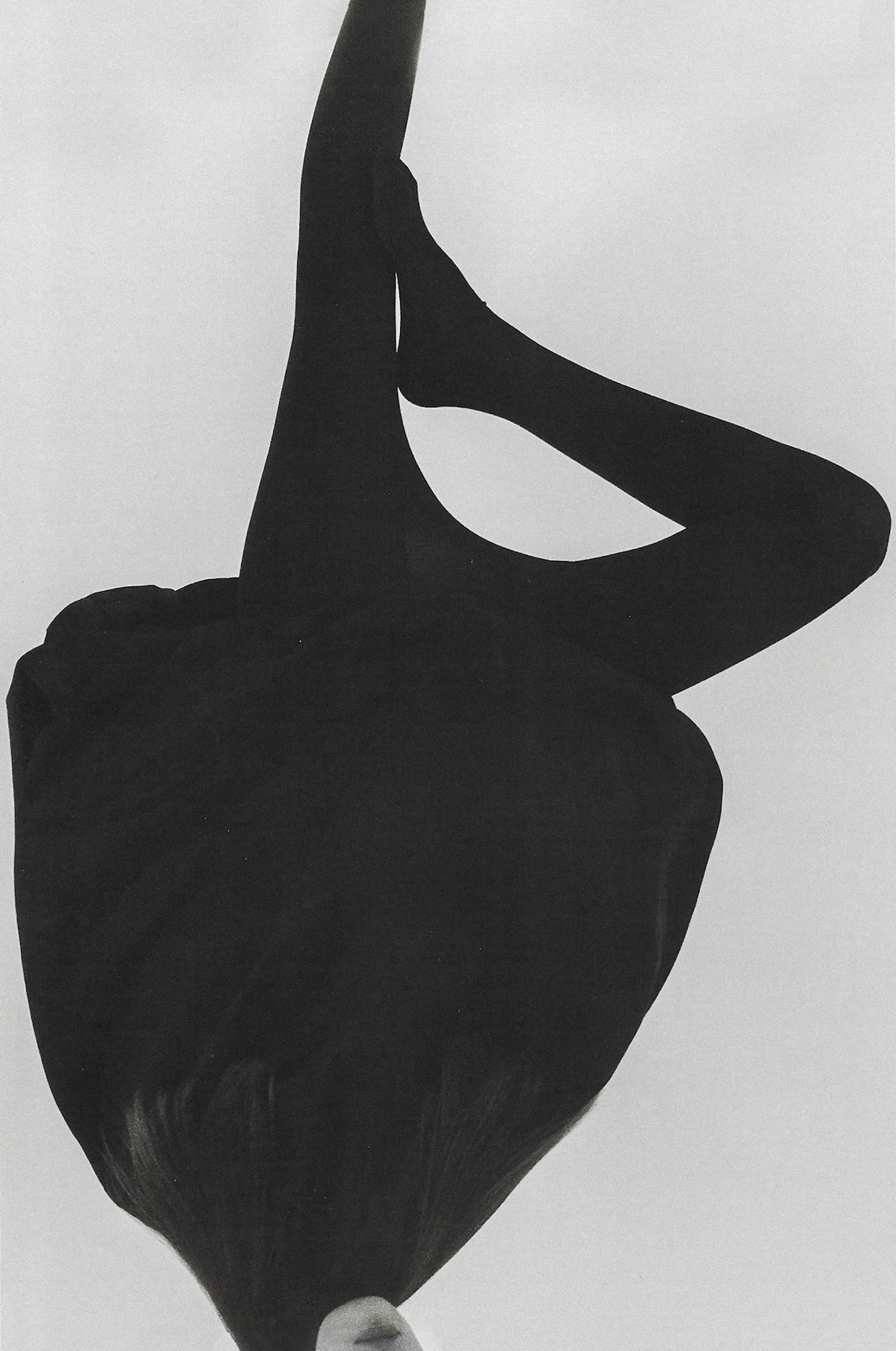 Black and white portrait of a person in black clothing captured upside down against a minimal light background