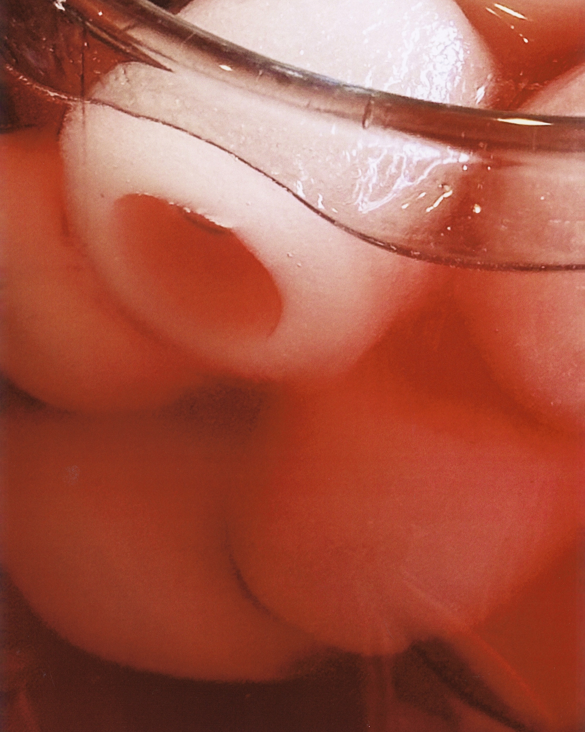 Close-up of a glass filled with a red beverage and ice balls, showcasing refreshing drink details.