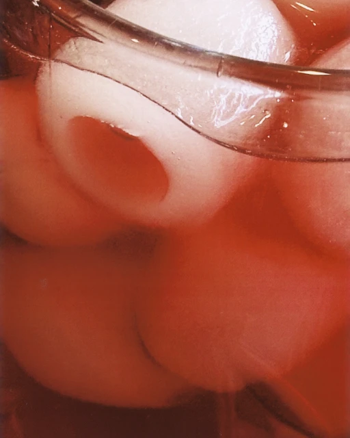 Close-up of a glass filled with a red beverage and ice balls, showcasing refreshing drink details.