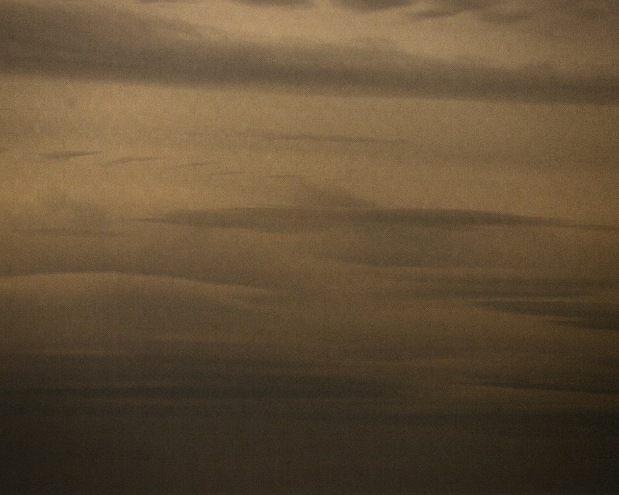 Atmospheric view of soft, sepia-toned clouds filling the frame in horizontal layers with varying shades and densities.
