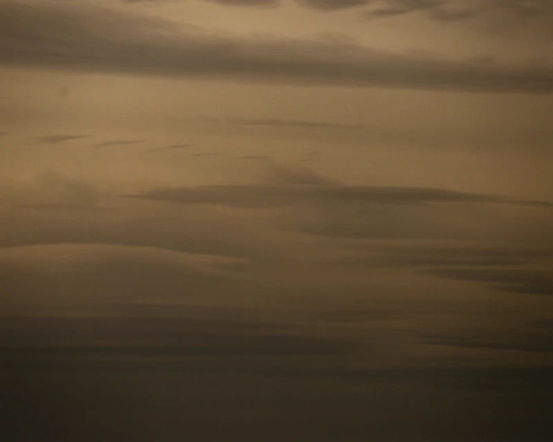 Atmospheric view of soft, sepia-toned clouds filling the frame in horizontal layers with varying shades and densities.