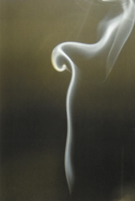Elegant, swirling white smoke against a gradient background of gold and dark gray, creating a flowing, abstract, ethereal visual.