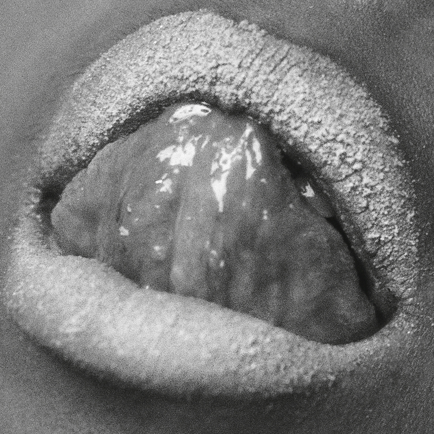 Close-up shot of human lips covered in silver glitter, with a tongue extending out, creating a textured and visually striking image.