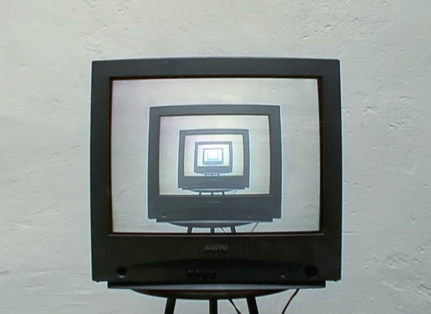 A black cathode-ray television on a stand shows a recursive screen display, diminishing into the distance, against a white wall.