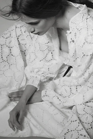 Close-up portrait of a woman in a textured white lace dress with puffed sleeves photographed by Cecilia Duarte.