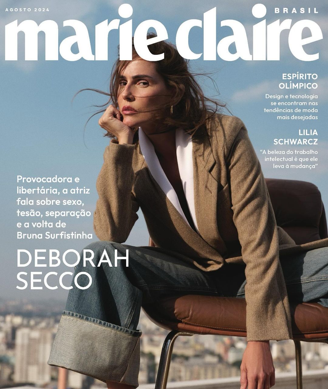 Deborah Secco seated in a chair on a rooftop wearing a brown blazer, white shirt, and cuffed jeans, shot by Cecilia Duarte.