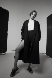Model in long black coat and white shirt posing in studio by photographer Cecilia Duarte