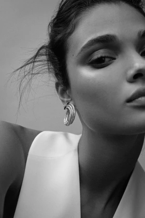 Close-up portrait of a woman wearing a structured white top and statement pavé hoop earrings by photographer Cecilia Duarte.