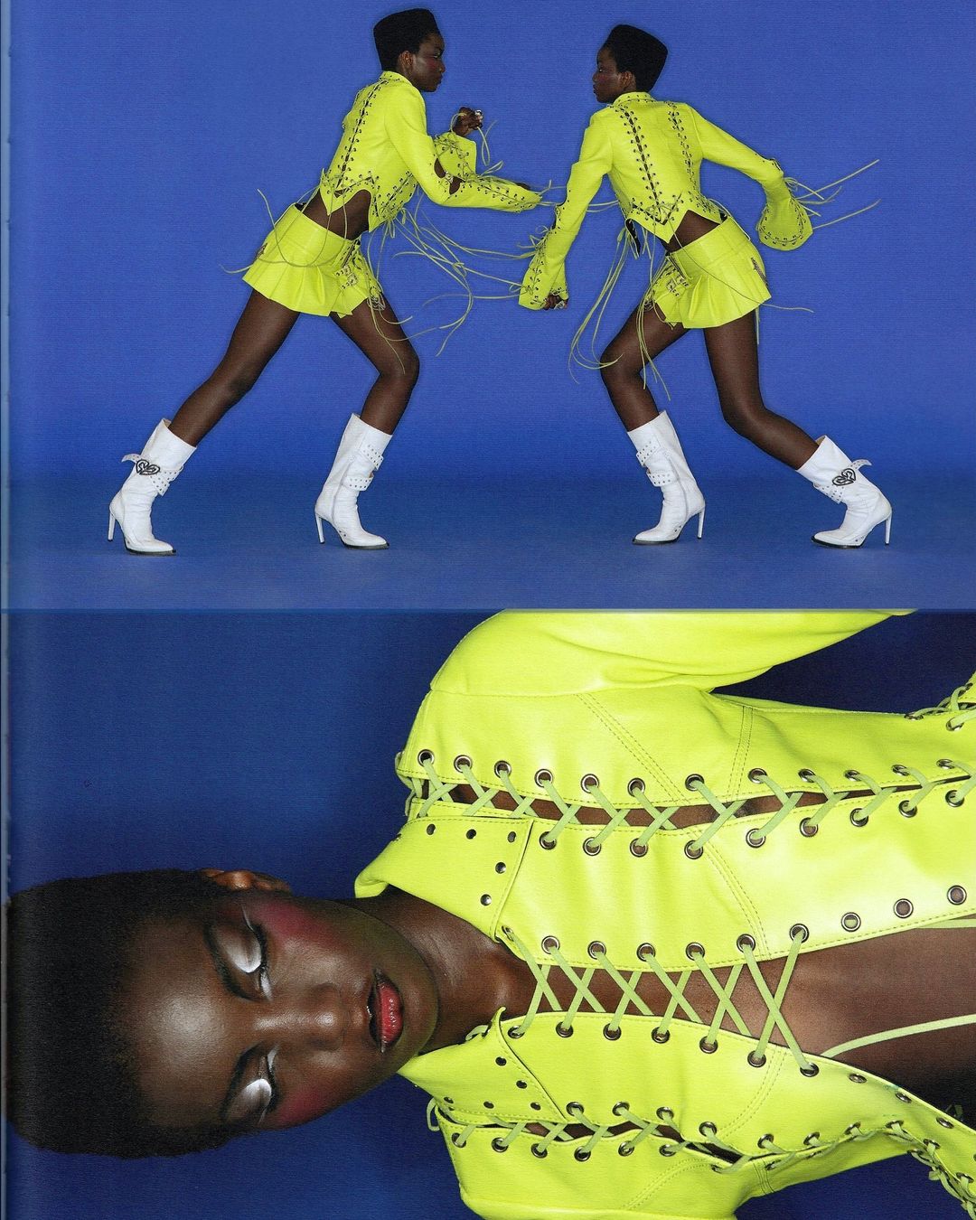 Two African American fashion models pose against a blue backdrop wearing matching neon yellow outfits and white boots in a studio shot.