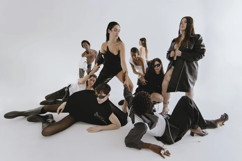 Diverse group of models in fashionable attire pose in a bright photo studio, showcasing a mix of textures, styles, and modern clothing designs.