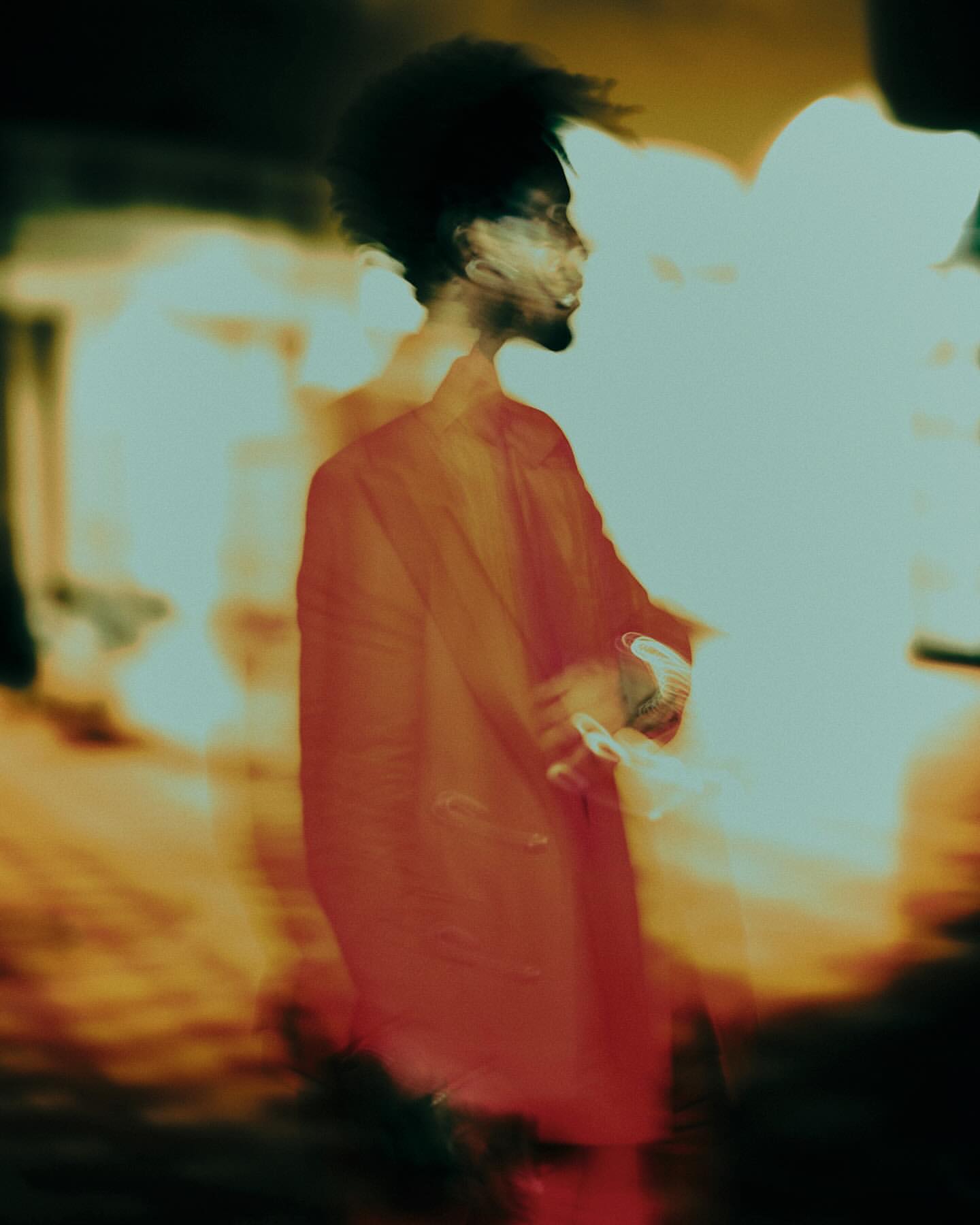 Portrait of a man in a red jacket captured in motion with vibrant warm light streaks by Dani Pujalte.