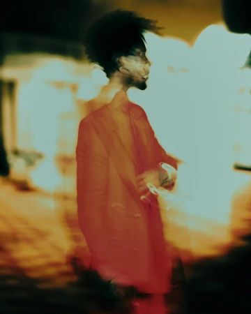 Portrait of a man in a red jacket captured in motion with vibrant warm light streaks by Dani Pujalte.