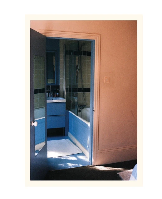 Bathroom interior with blue vanity and bathtub, viewed through an open door, showcasing the design and layout of the space.