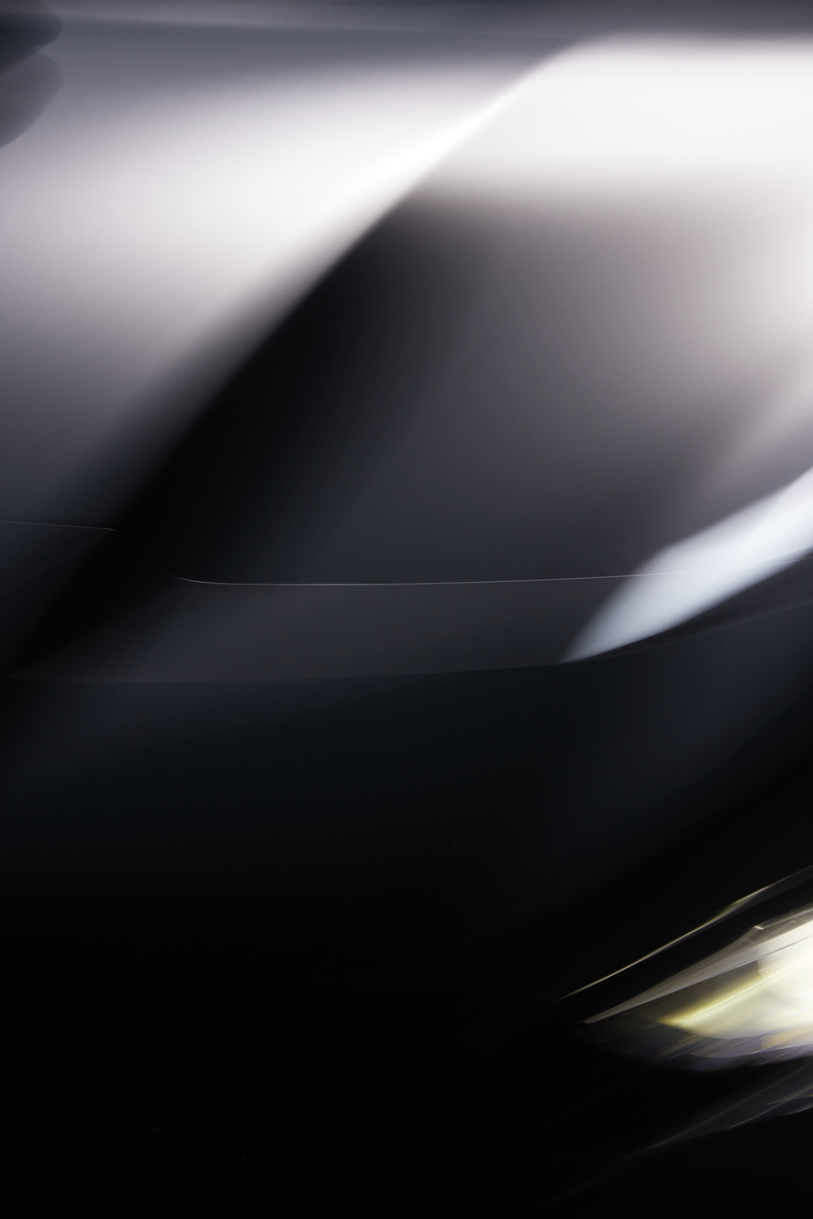 Abstract image featuring blurred lights and dark contrasts, creating a sense of movement and mystery in a vertical format.