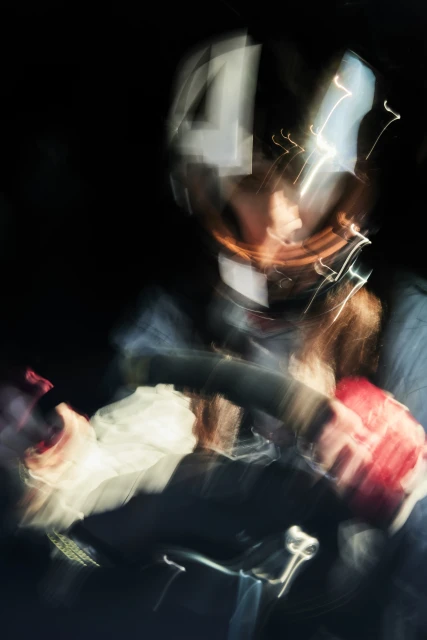 Motion-blurred image of a cyclist at night, showing a figure on a bicycle, captured with long exposure and artistic blur effects.