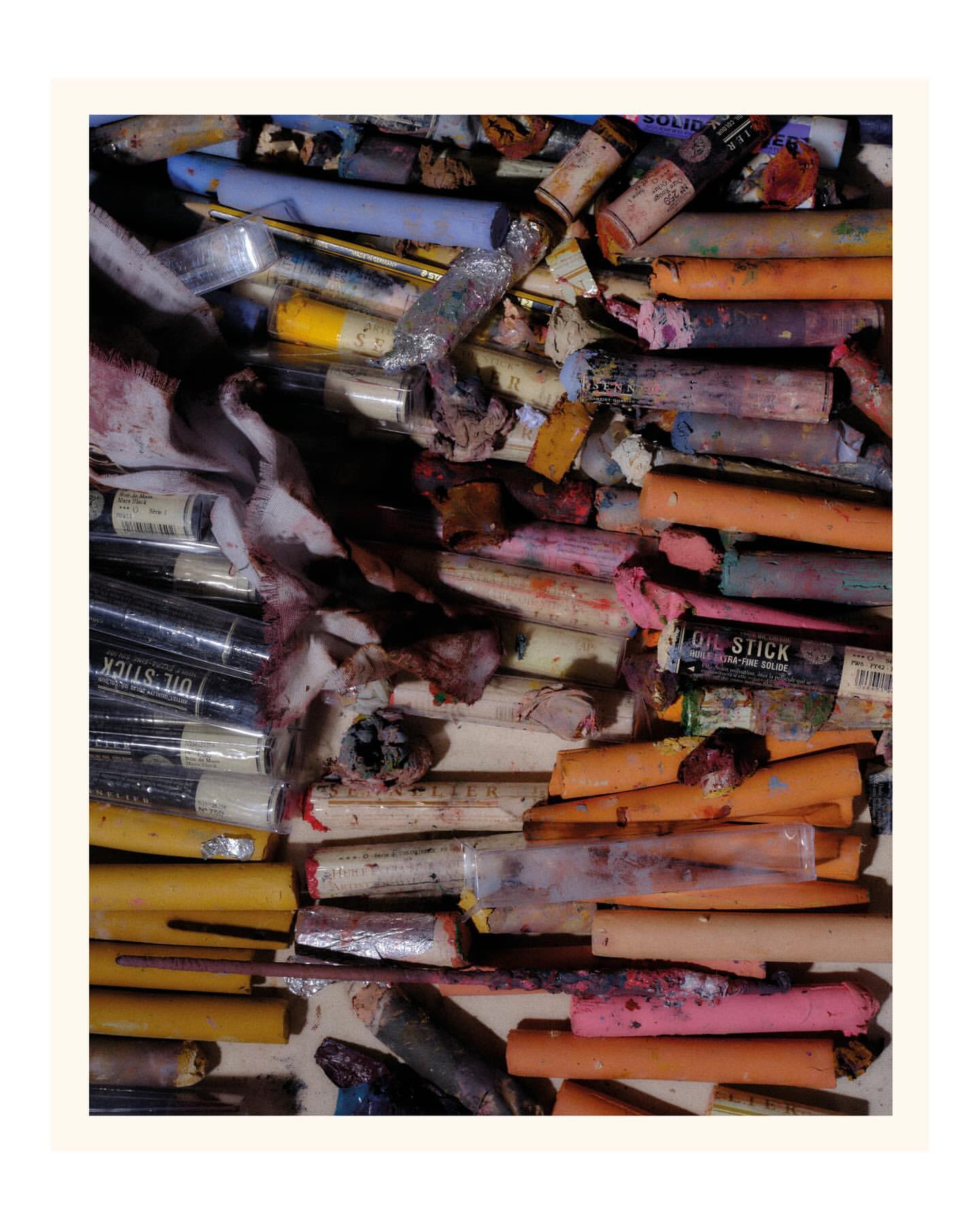 Array of colorful artist oil sticks in a variety of colors and sizes arranged in an untidy collection on a neutral surface.