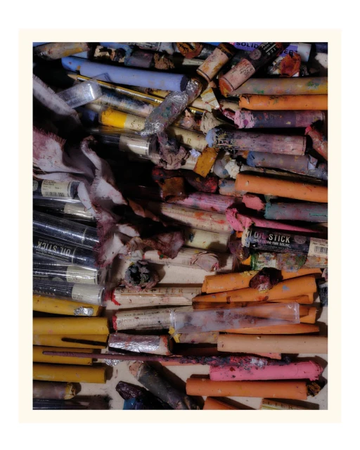 Array of colorful artist oil sticks in a variety of colors and sizes arranged in an untidy collection on a neutral surface.
