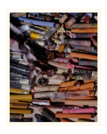 Array of colorful artist oil sticks in a variety of colors and sizes arranged in an untidy collection on a neutral surface.