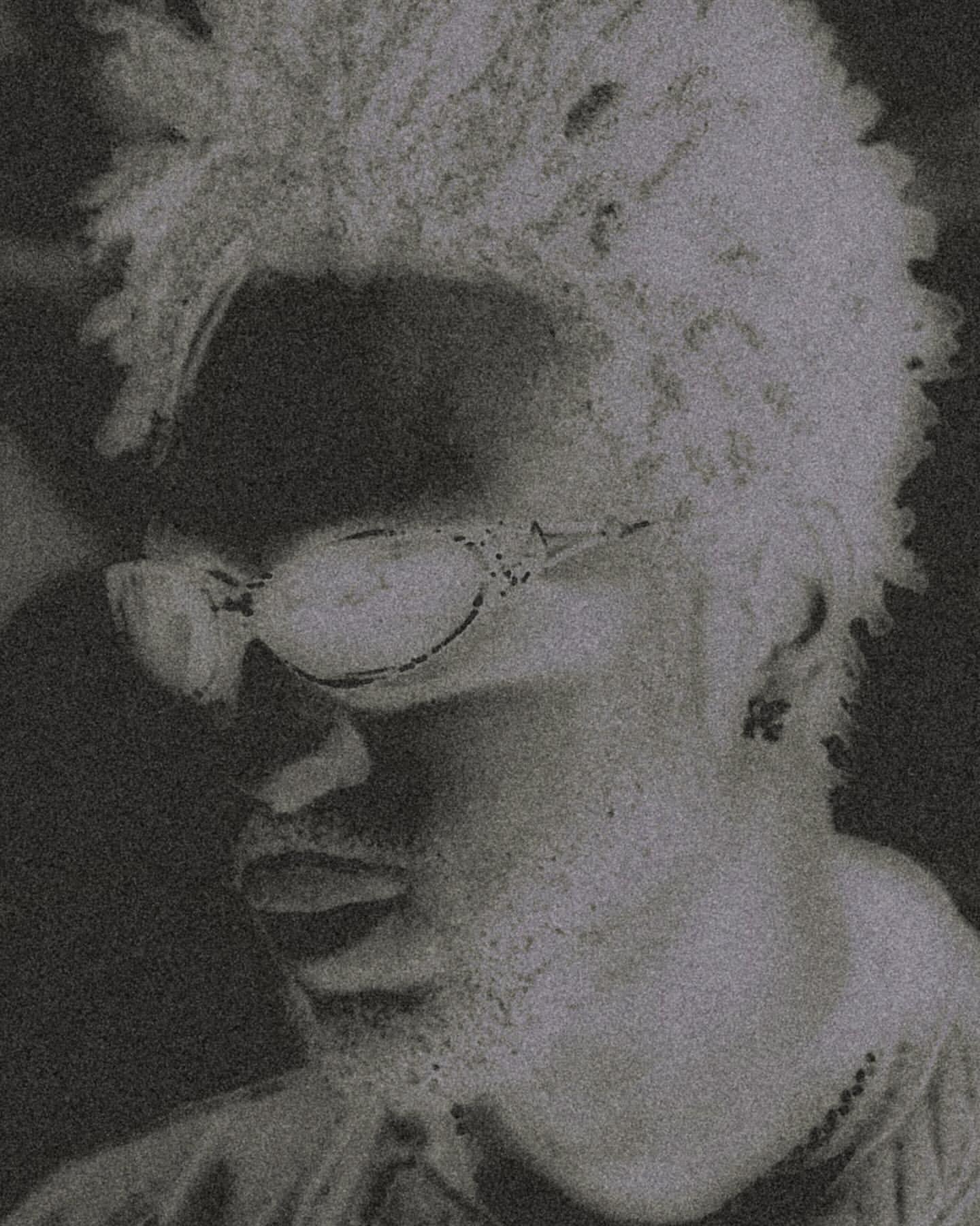 Headshot of a man with short curly hair and glasses in black and white. Artistic rendering and close-up framing.