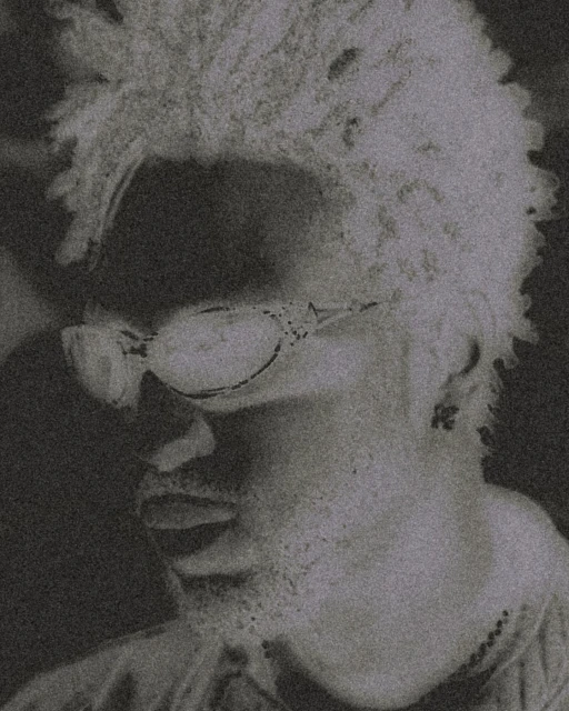 Headshot of a man with short curly hair and glasses in black and white. Artistic rendering and close-up framing.