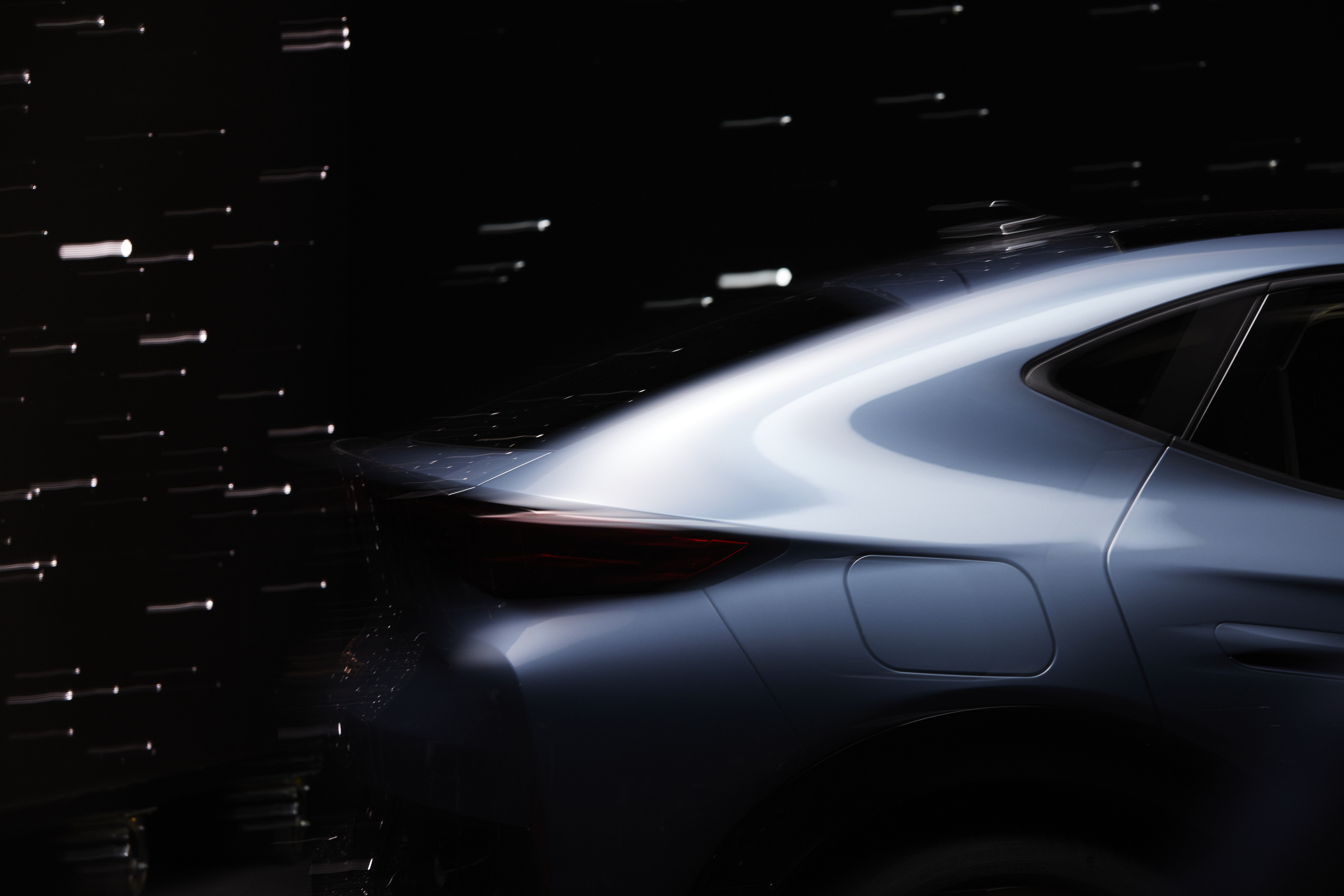 Sleek blue car in motion with motion blur and dark background, showcasing automotive design and speed, elegant lines.