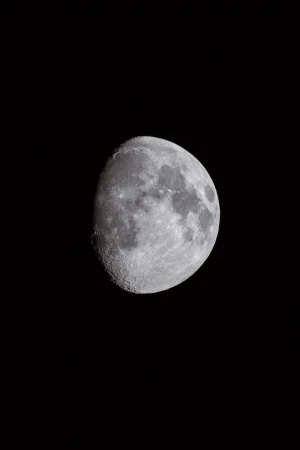 Detailed photograph of the moon with craters against a black sky, showcasing its surface texture and lunar details.