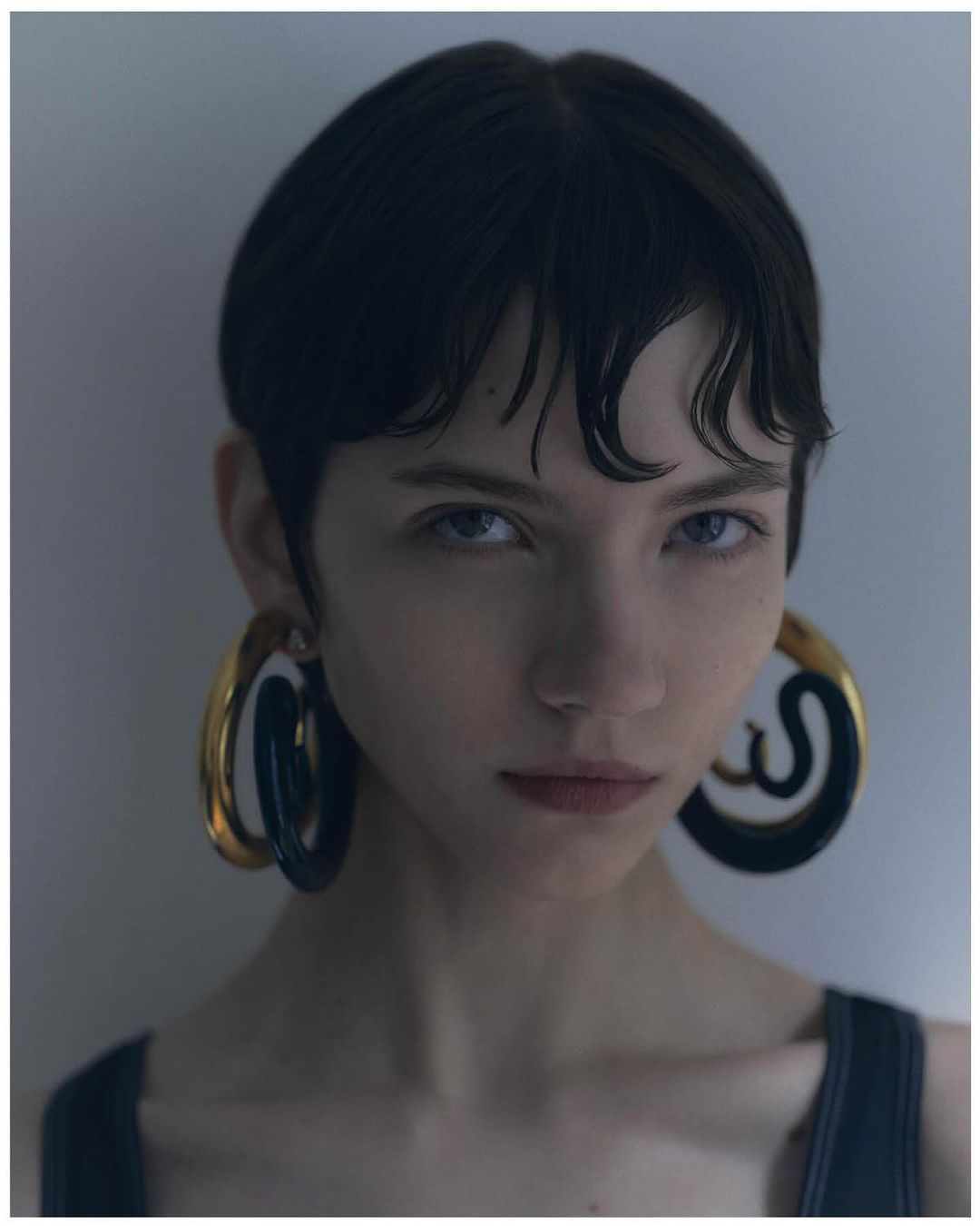 Portrait of a woman with short dark hair wearing large chunky hoop earrings by photographer Dani Pujalte.
