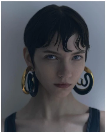 Portrait of a woman with short dark hair wearing large chunky hoop earrings by photographer Dani Pujalte.