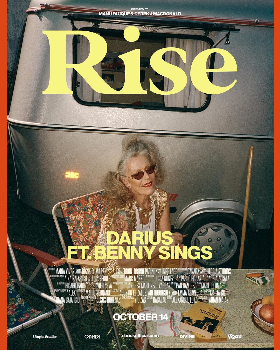 An elderly woman in a floral top poses in a folding chair in front of a camper, promoting Darius ft. Benny Sings' new song Rise.