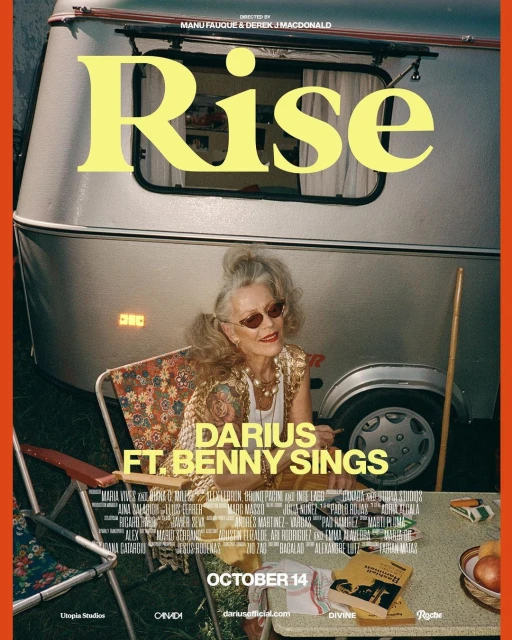 An elderly woman in a floral top poses in a folding chair in front of a camper, promoting Darius ft. Benny Sings' new song Rise.