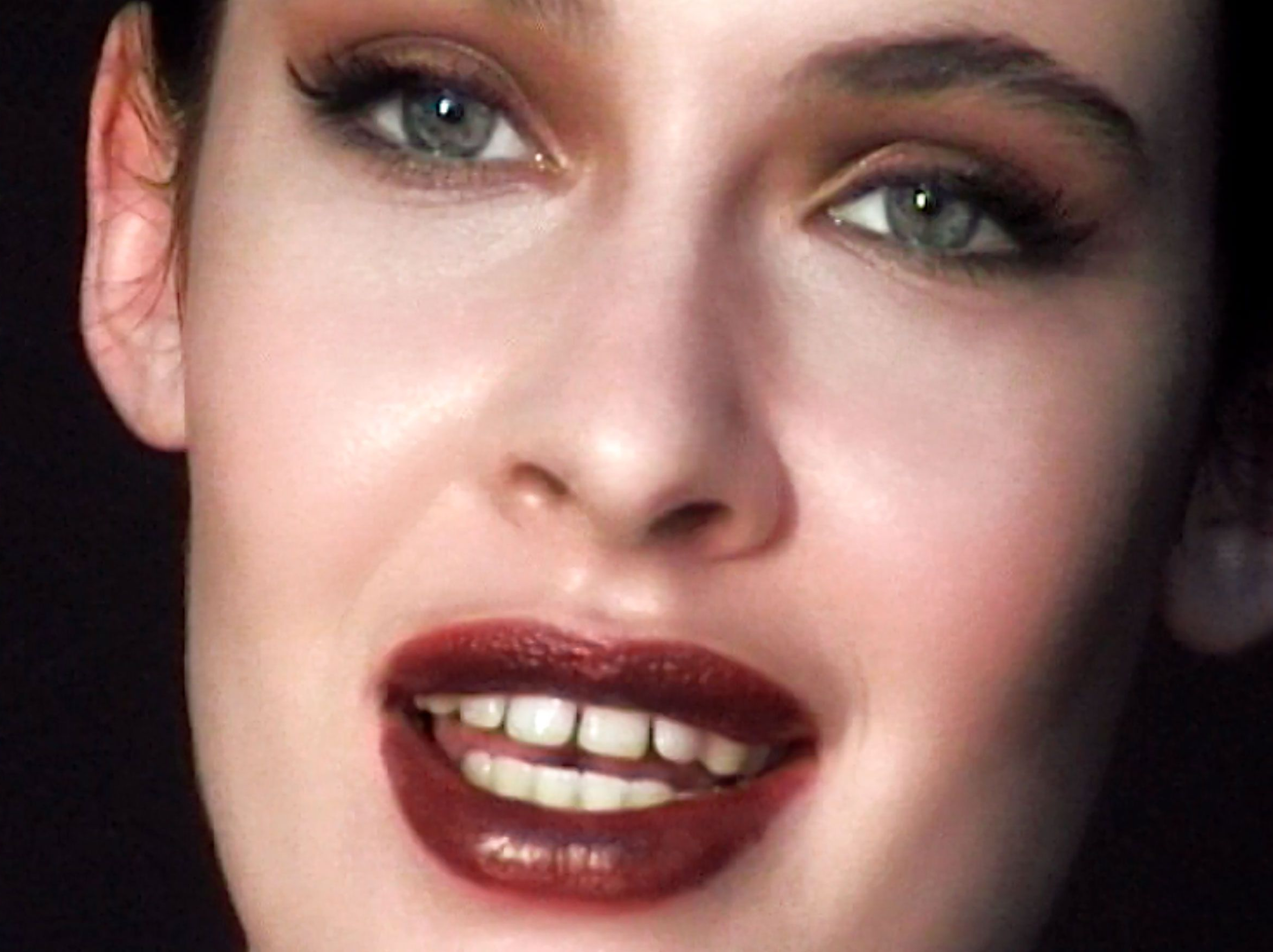 Close-up portrait of a woman with dark red lipstick and winged eyeliner against a dark background, photographed by Mar Ordonez.