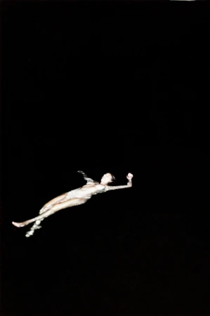 Artistic photograph of a female figure in an aquatic pose against a stark black background, creating a striking contrast and ethereal effect.