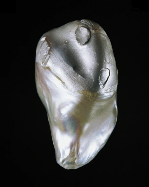 Iridescent baroque pearl close-up on a dark background. Lustrous gem with unique form, showing color play and natural imperfections.