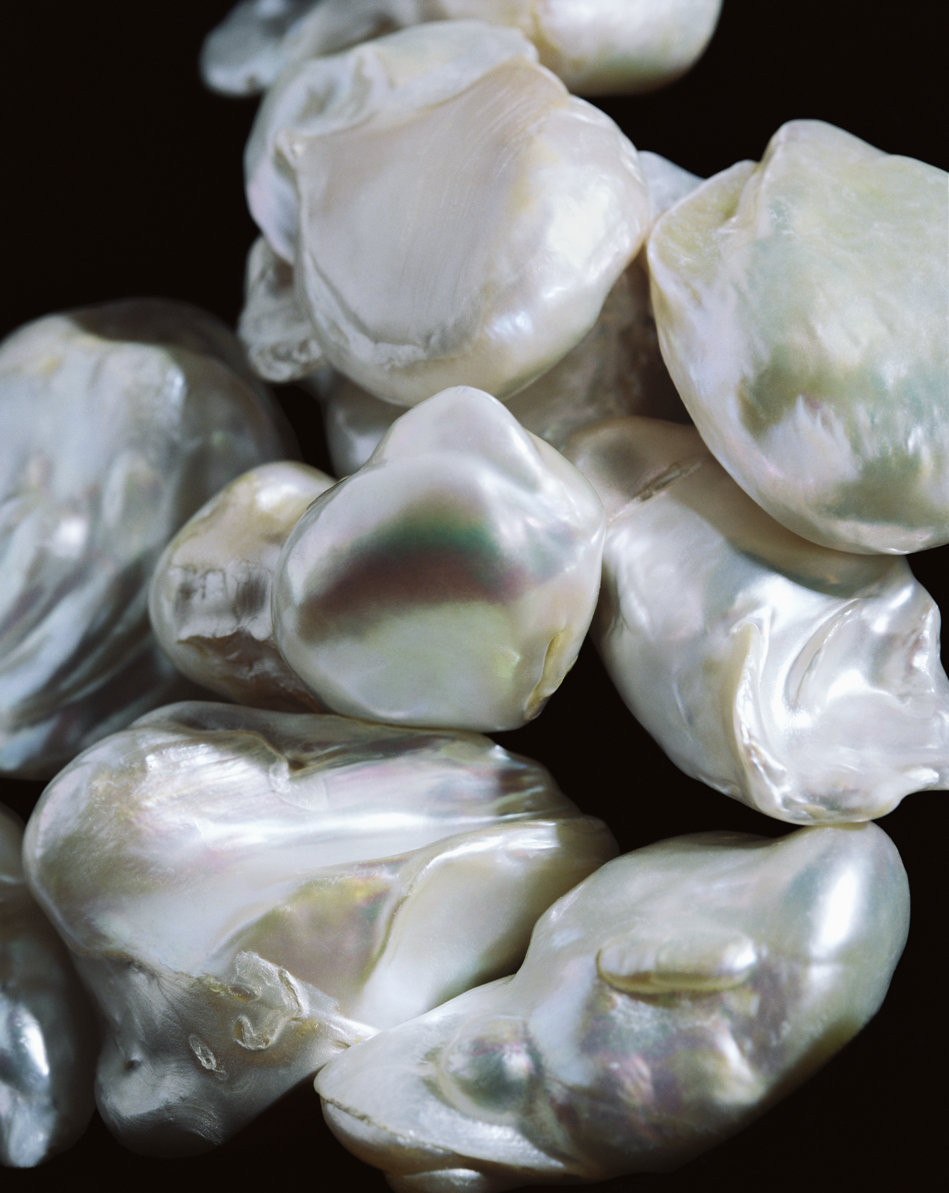 Close-up studio shot of lustrous white baroque pearls with unique shapes, reflecting light in an abstract composition.