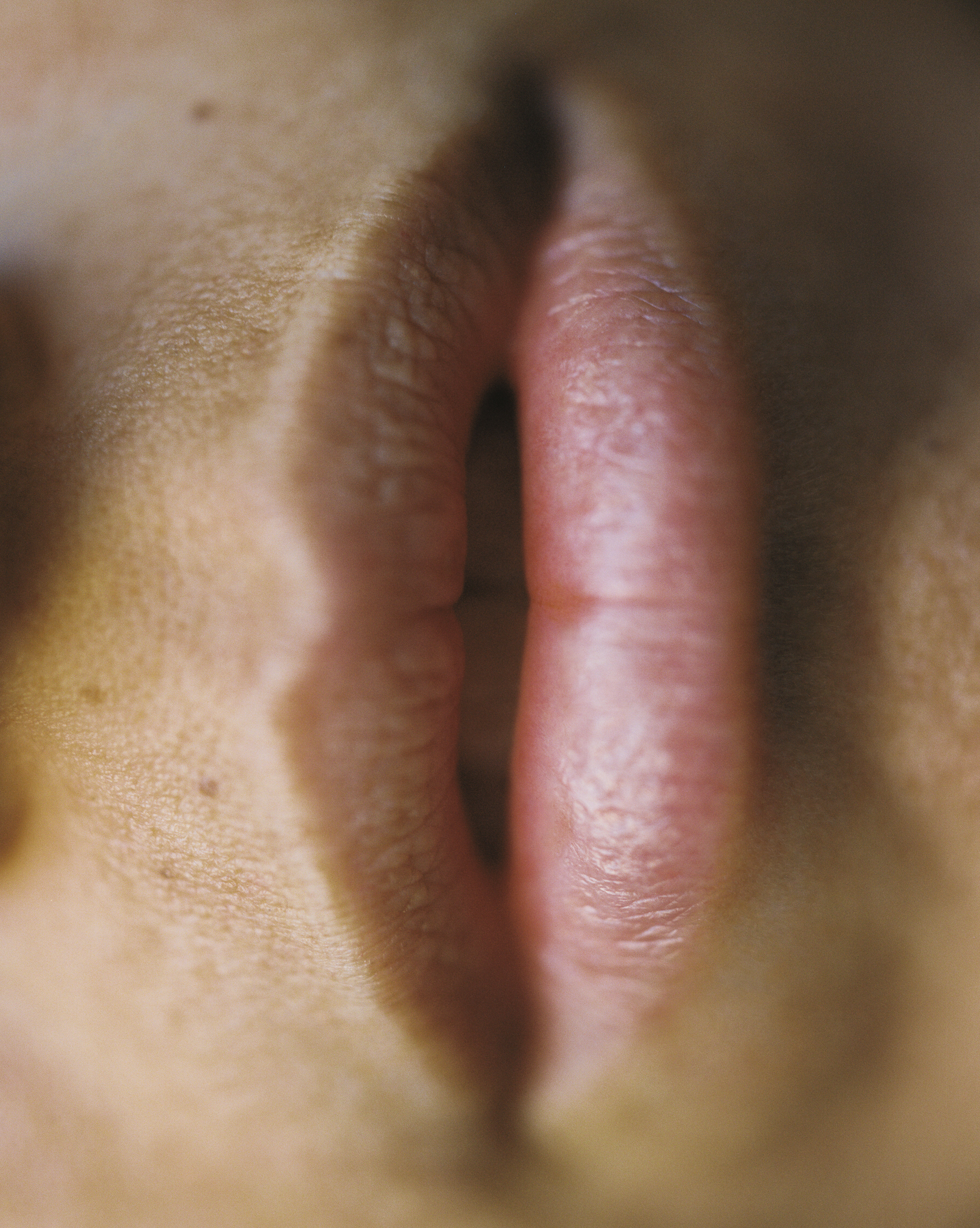 Close-up of human lips with lipstick, emphasizing texture and detail in a minimalist composition. The image highlights natural skin tones.
