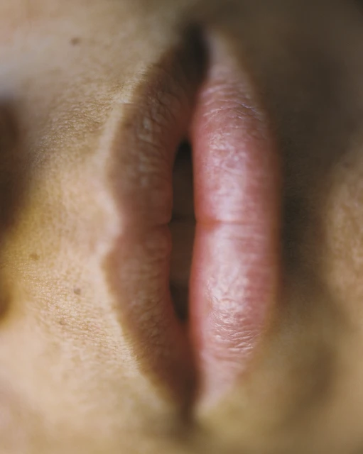 Close-up of human lips with lipstick, emphasizing texture and detail in a minimalist composition. The image highlights natural skin tones.