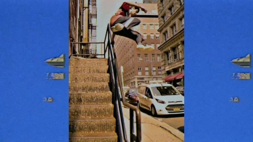Young man mid-air doing a skateboarding trick over a railing, urban street background with buildings, van, captured with vivid color grading.