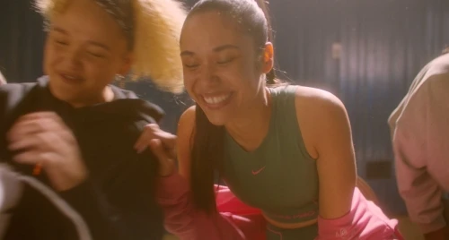 Group of diverse smiling women in sportswear in an indoor setting, suggesting fitness, sports, or active lifestyle themes. 