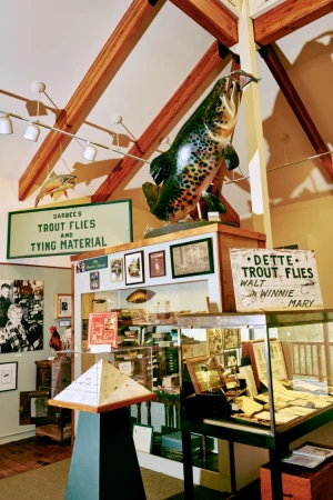 Interior view of a museum display featuring a large trout sculpture, vintage signage, and various artifacts related to fly fishing.
